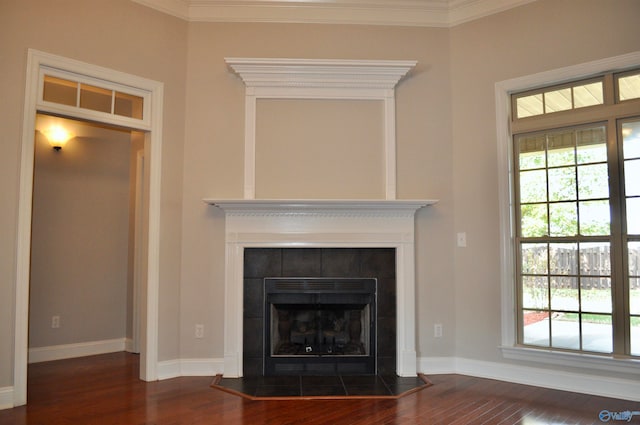 room details featuring a tiled fireplace, wood-type flooring, and crown molding