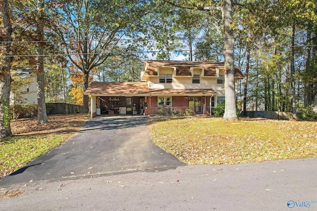 front of property with a front yard, a carport, and covered porch