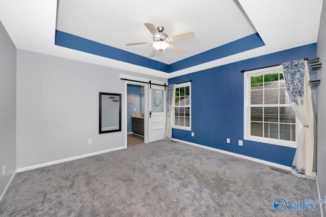 204 Hollington Dr, Huntsville, AL 35811 - unfurnished bedroom featuring a raised ceiling, a barn door, carpet flooring, connected bathroom, and ceiling fan
