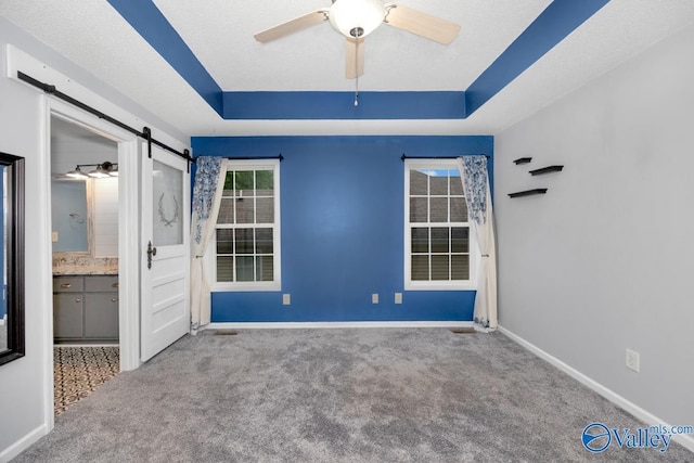 204 Hollington Dr, Huntsville, AL 35811 - unfurnished bedroom featuring a barn door, carpet, ensuite bathroom, a raised ceiling, and a ceiling fan