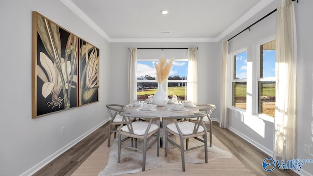 dining area with light wood-type flooring and crown molding