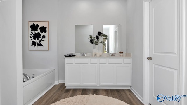 bathroom with hardwood / wood-style floors, a washtub, and vanity