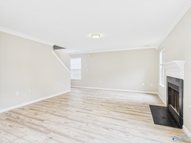 202 Declaration Cir, Madison, AL 35758 - unfurnished living room featuring light wood finished floors, healthy amount of natural light, a tiled fireplace, and ornamental molding