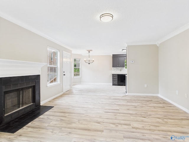 202 Declaration Cir, Madison, AL 35758 - unfurnished living room with ornamental molding, a tiled fireplace, a chandelier, and light wood-style flooring