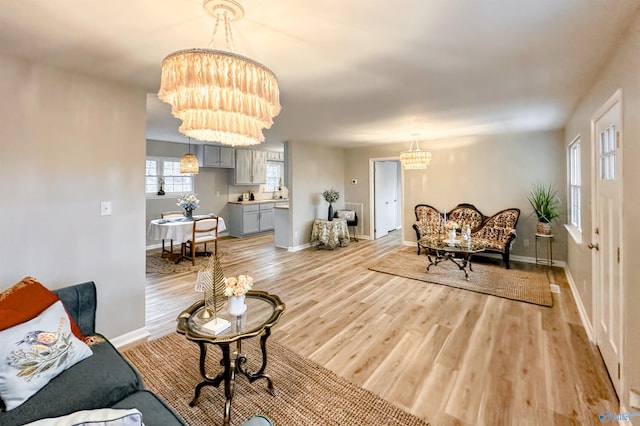 living area featuring a notable chandelier, light wood-style floors, and baseboards