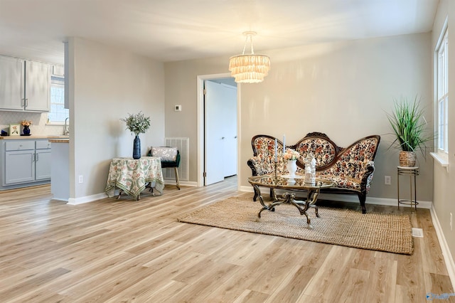 sitting room with light wood-type flooring, baseboards, and a chandelier