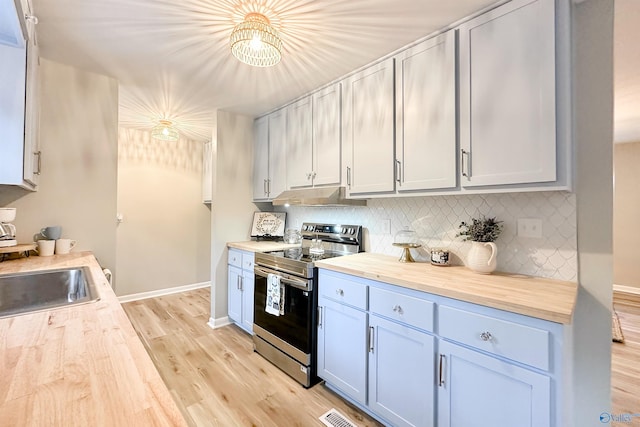 kitchen featuring under cabinet range hood, light wood finished floors, stainless steel range with electric cooktop, and wood counters