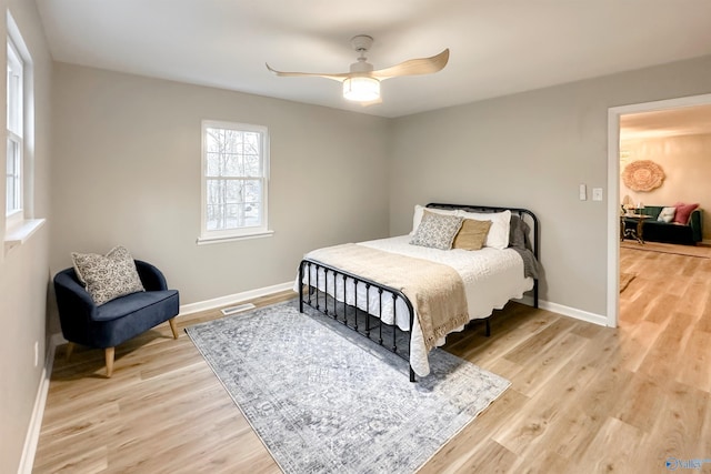 bedroom featuring a ceiling fan, visible vents, light wood-style floors, and baseboards