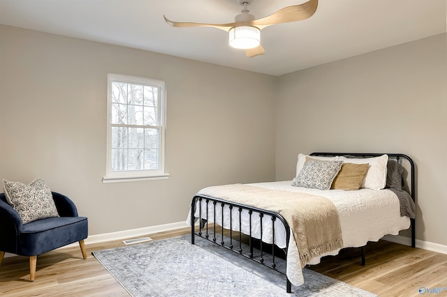 bedroom with a ceiling fan, light wood-style floors, visible vents, and baseboards