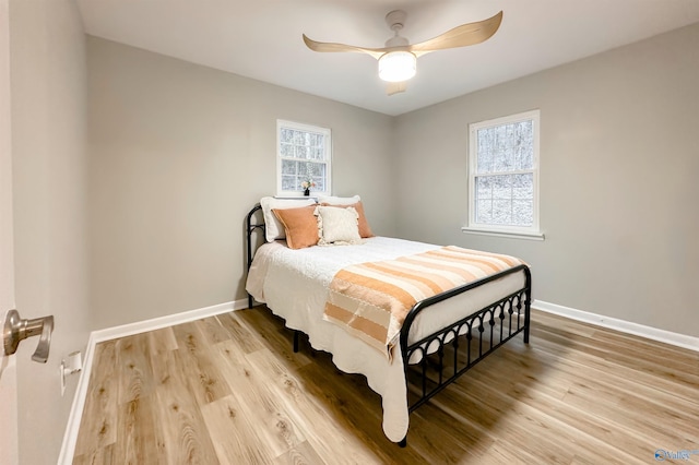 bedroom with multiple windows, baseboards, and wood finished floors