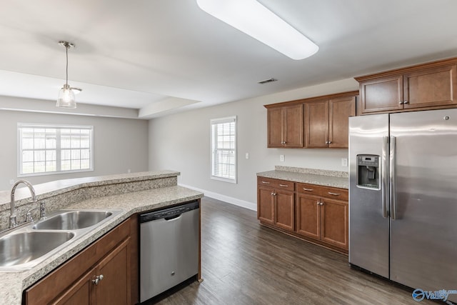 kitchen featuring light countertops, dark wood-type flooring, appliances with stainless steel finishes, a sink, and hanging light fixtures