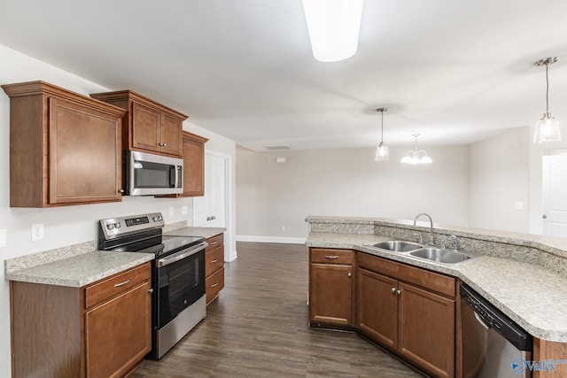 kitchen with hanging light fixtures, baseboards, a sink, appliances with stainless steel finishes, and dark wood-style floors