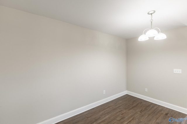 empty room with dark wood-style flooring, baseboards, and a chandelier