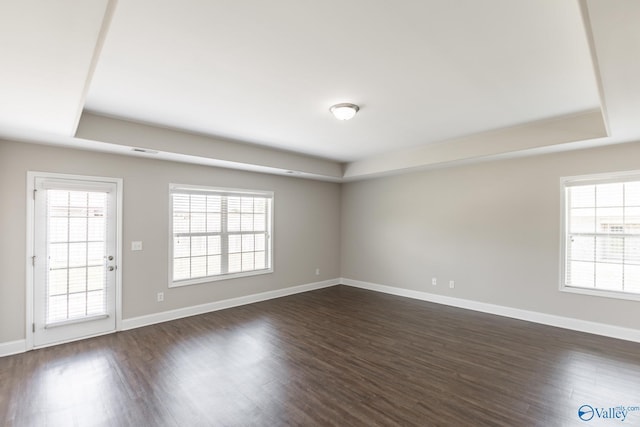 spare room featuring dark wood-style floors, a tray ceiling, and visible vents