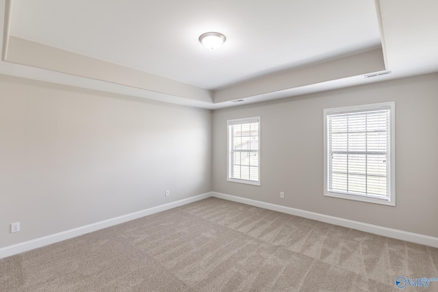 spare room featuring light carpet, visible vents, and baseboards