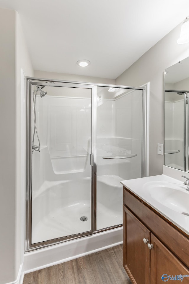 full bath featuring a stall shower, wood finished floors, vanity, and recessed lighting