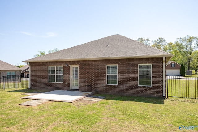rear view of property with a lawn, a patio area, fence, brick siding, and a shingled roof