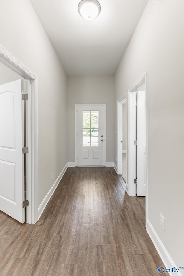 doorway to outside featuring baseboards and wood finished floors