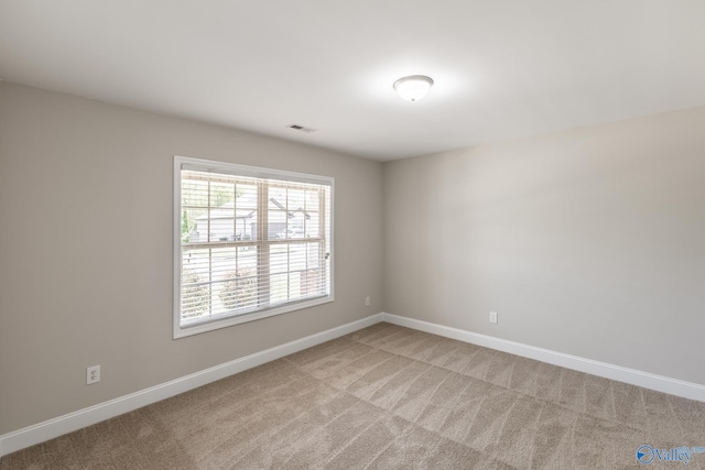 spare room with visible vents, light colored carpet, and baseboards