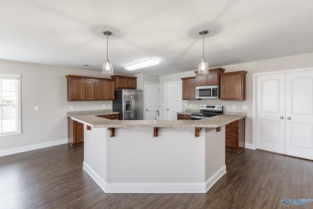 kitchen featuring a kitchen bar, dark wood-style flooring, light countertops, stainless steel appliances, and baseboards