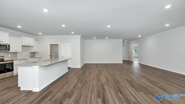 kitchen with dark wood-type flooring, light stone counters, a center island with sink, appliances with stainless steel finishes, and white cabinets