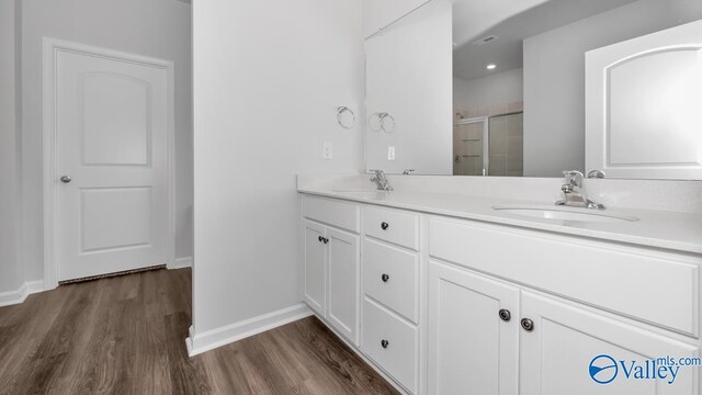 bathroom with hardwood / wood-style flooring, vanity, and walk in shower