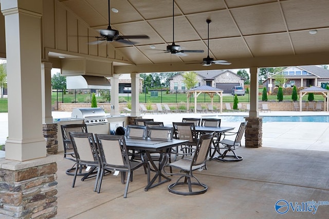 view of patio / terrace with a community pool, an outdoor kitchen, a grill, ceiling fan, and a gazebo