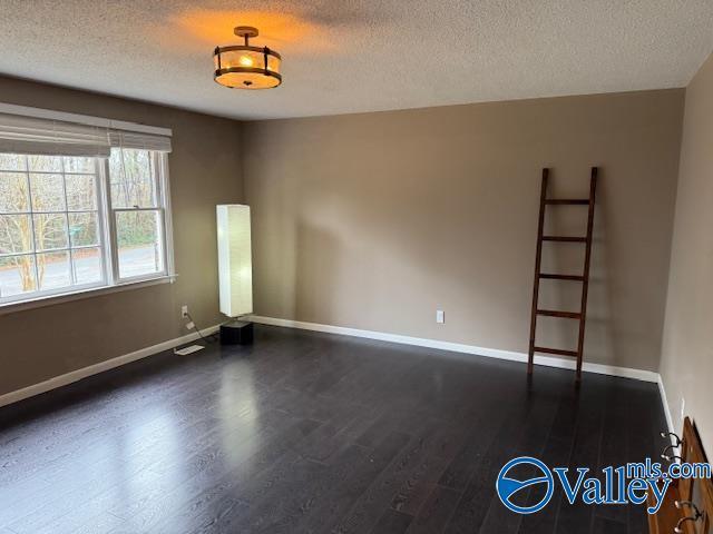 2500 Montezuma Dr, Gadsden, AL 35904 - unfurnished room featuring dark wood-style floors, baseboards, and a textured ceiling