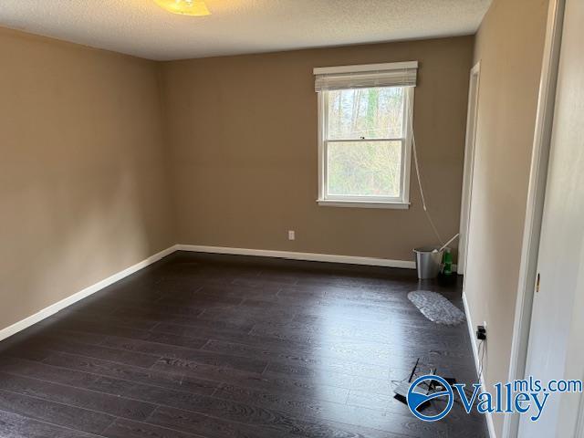 2500 Montezuma Dr, Gadsden, AL 35904 - spare room featuring a textured ceiling, baseboards, and dark wood-style flooring