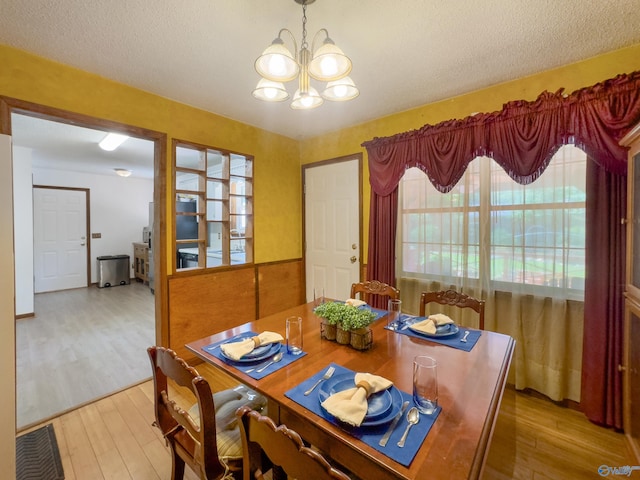 dining space featuring a textured ceiling, a chandelier, and light hardwood / wood-style floors