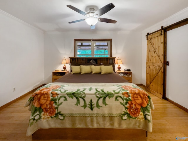 bedroom featuring light wood-type flooring, ceiling fan, crown molding, and a barn door