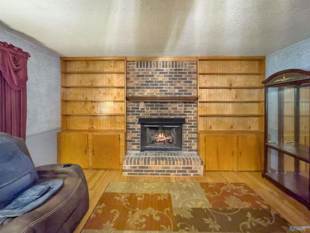 living room with wood-type flooring, a textured ceiling, and a fireplace