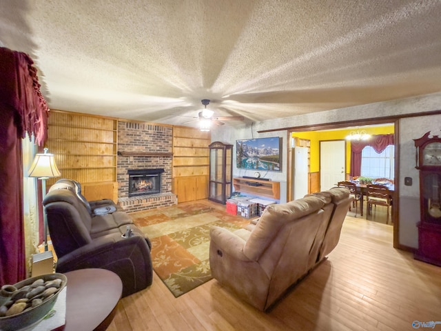 living room with a brick fireplace, a textured ceiling, ceiling fan, built in features, and hardwood / wood-style flooring