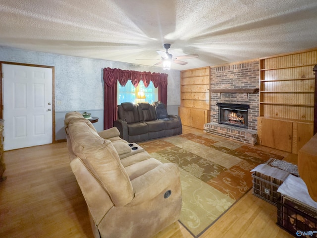 living room featuring a textured ceiling, hardwood / wood-style floors, ceiling fan, and a brick fireplace