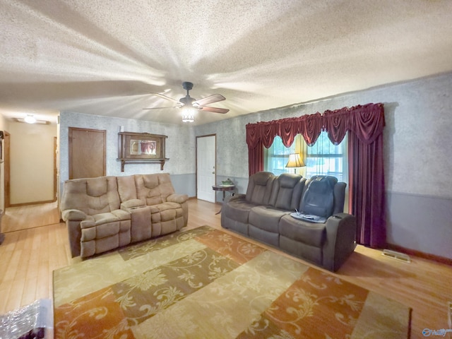 living room featuring ceiling fan, hardwood / wood-style flooring, and a textured ceiling