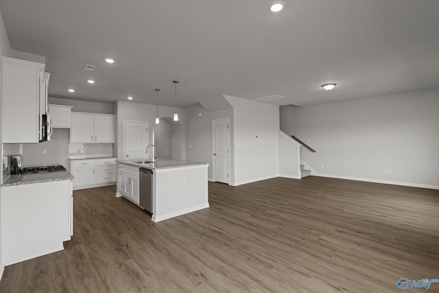 kitchen with pendant lighting, an island with sink, decorative backsplash, white cabinetry, and appliances with stainless steel finishes