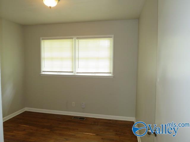 spare room with baseboards, visible vents, and wood finished floors