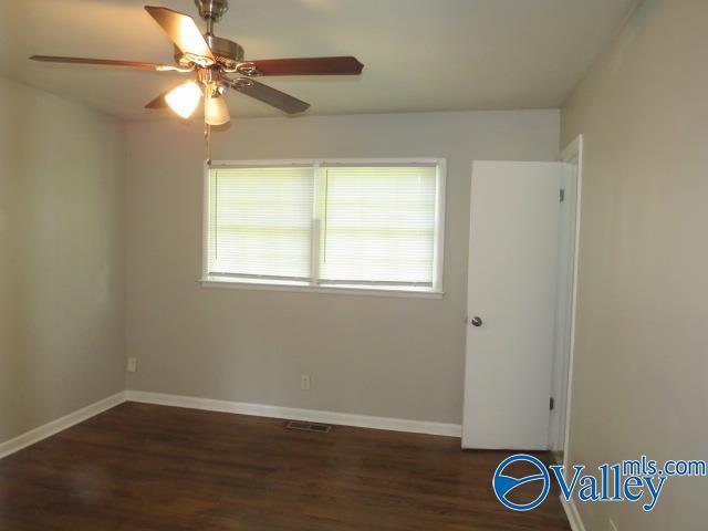 spare room featuring a ceiling fan, baseboards, visible vents, and wood finished floors