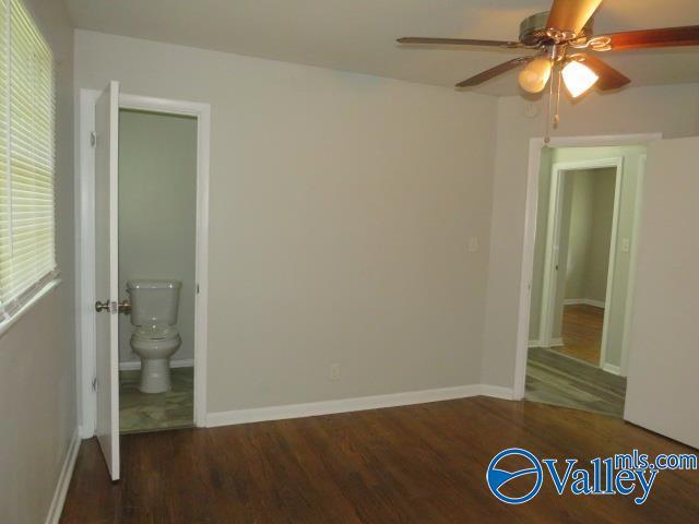 unfurnished bedroom with ensuite bathroom, ceiling fan, baseboards, and wood finished floors