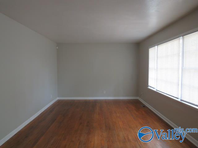 spare room featuring baseboards and wood finished floors