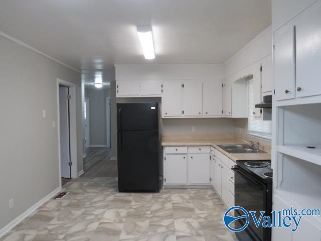 kitchen featuring white cabinets, light countertops, crown molding, black appliances, and a sink