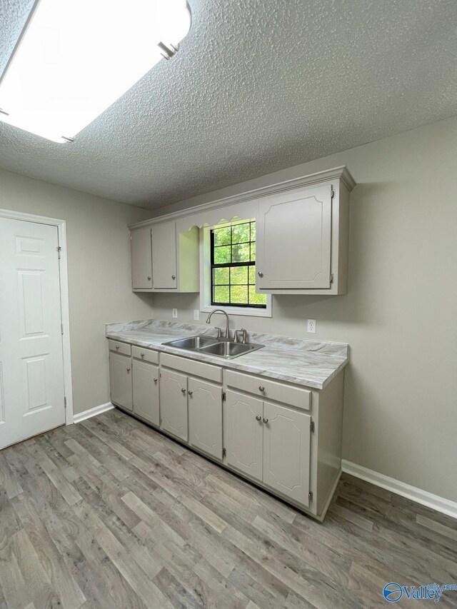 160 Guy Wilson Rd, Hazel Green, AL 35750 - kitchen featuring light countertops, a textured ceiling, light wood finished floors, and a sink