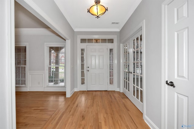 entryway featuring light wood-type flooring, crown molding, and french doors