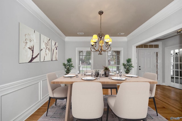 dining room with wood-type flooring, crown molding, and a notable chandelier