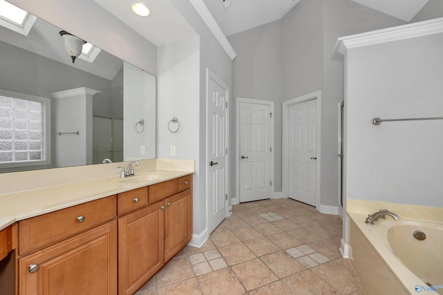 bathroom featuring vanity, a skylight, high vaulted ceiling, and tiled tub