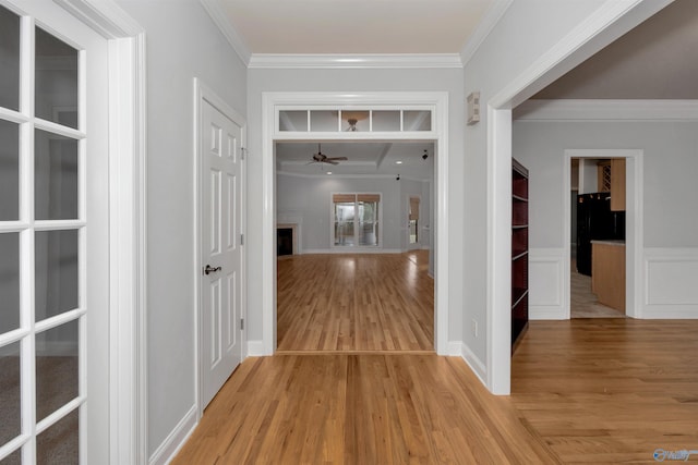 corridor with light hardwood / wood-style floors and ornamental molding