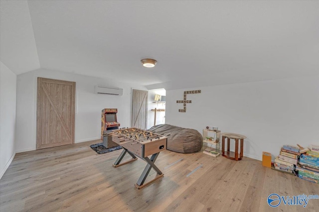 game room featuring vaulted ceiling, a wall mounted AC, baseboards, and wood finished floors