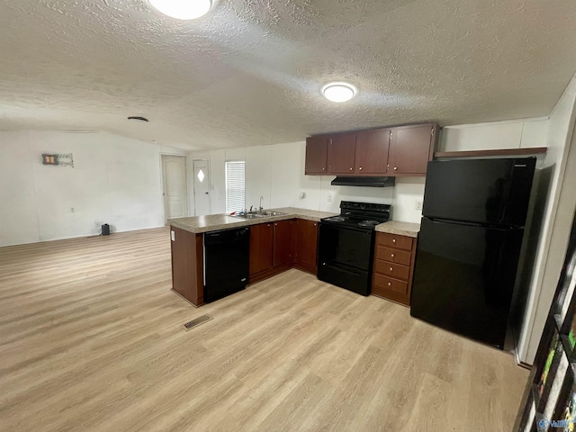 kitchen featuring a peninsula, a sink, light wood-style floors, light countertops, and black appliances