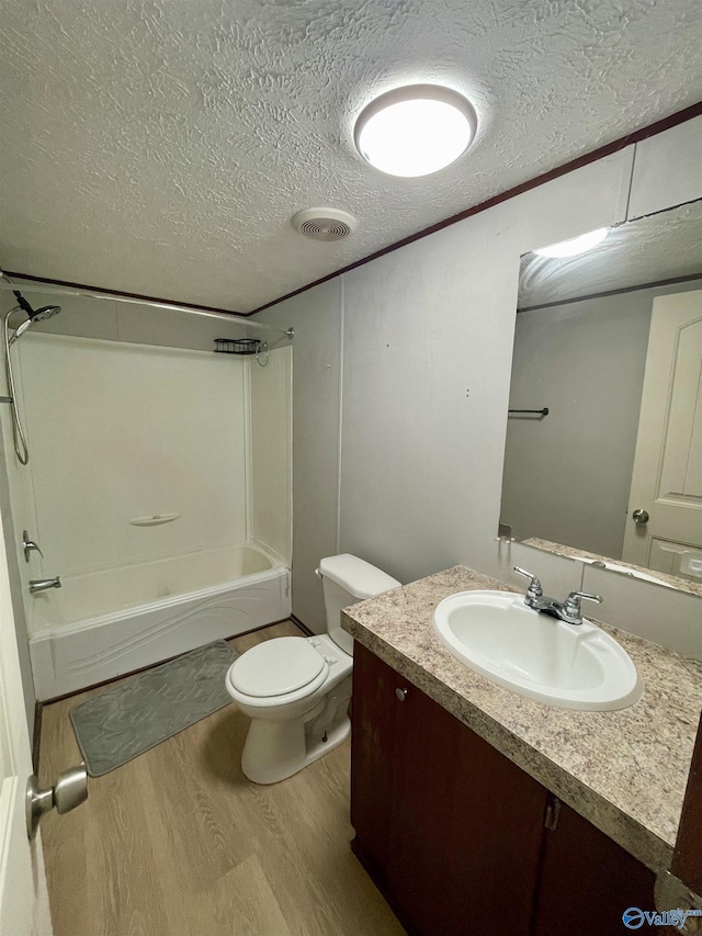 bathroom with toilet, wood finished floors,  shower combination, a textured ceiling, and vanity