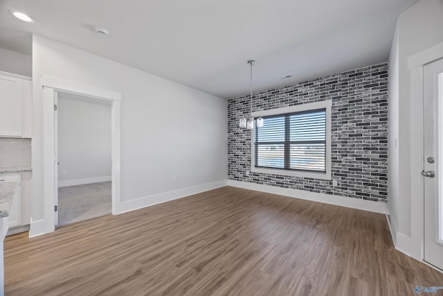 unfurnished dining area with brick wall and light hardwood / wood-style floors